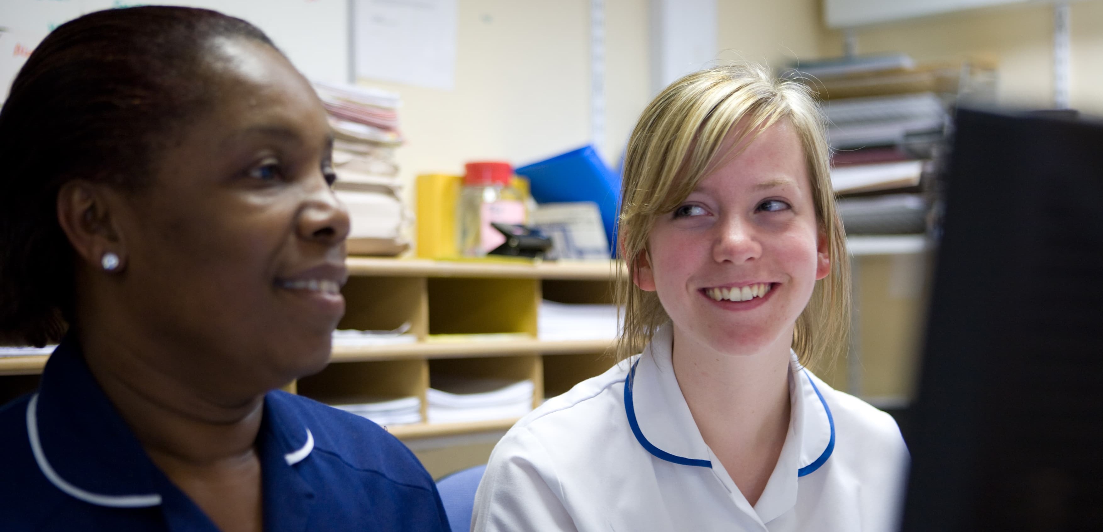 A photo of two nurses or midwives sitting together in a clinical setting.
